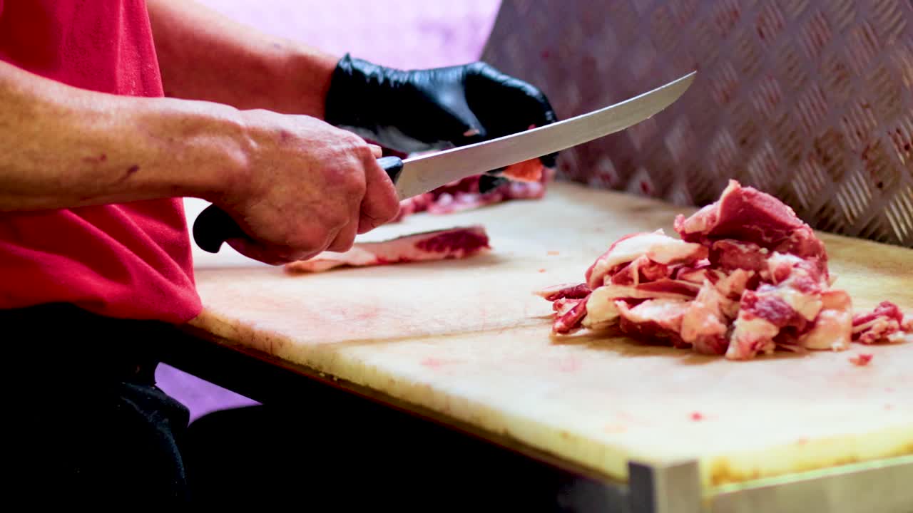 A butcher expertly slices meat on a wooden table in a well-lit environment, showcasing precision and craftsmanship in Melbourne, Australia