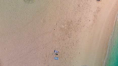 One-person-standing-on-the-beach-with-a-blue-and-white-towel-spread-over-the-sand-behind-them