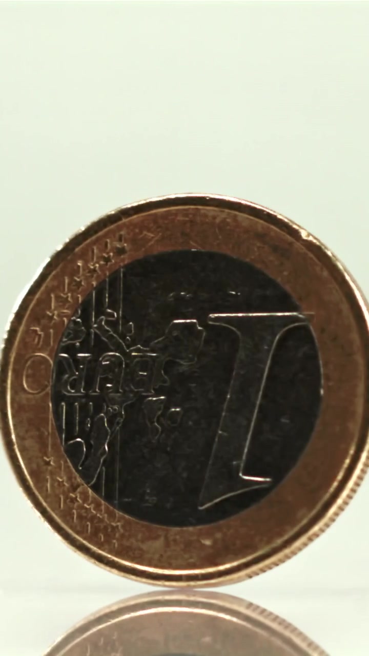 Primo piano di una moneta da un euro che gira su uno sfondo bianco