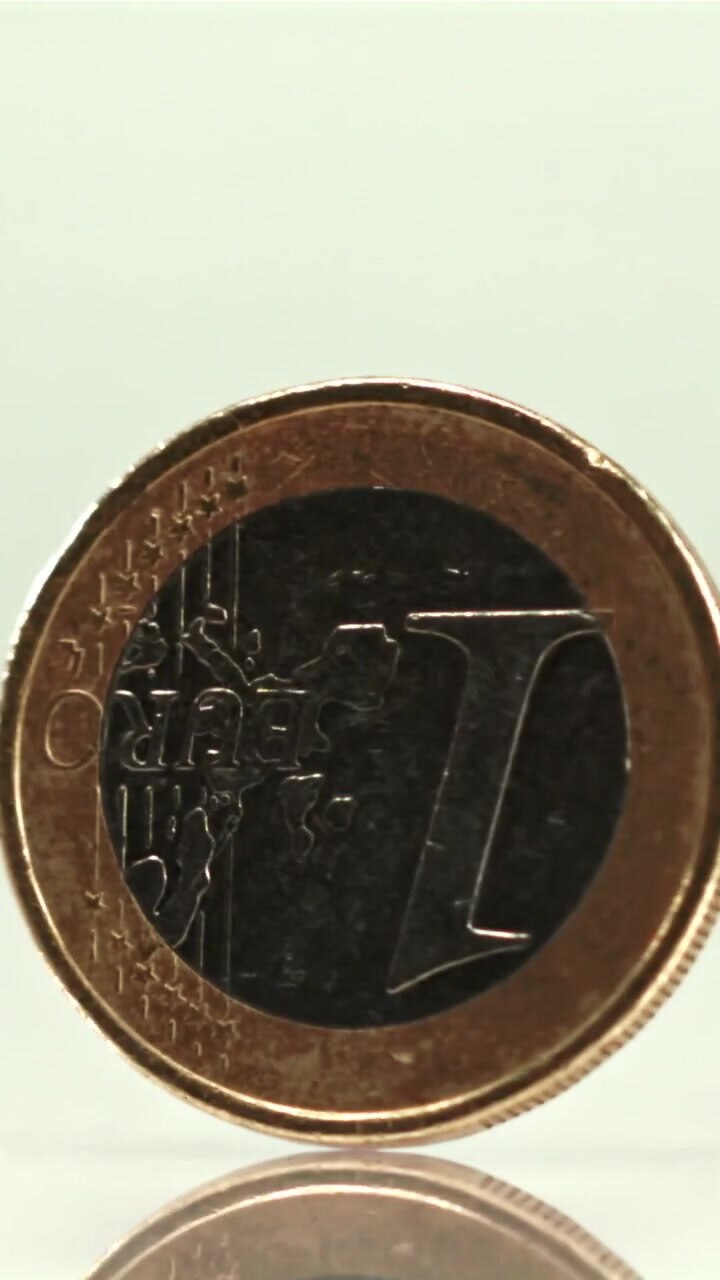 Primo piano di una moneta da un euro che gira su uno sfondo bianco