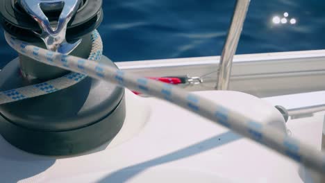 rope being pulled through a winch of a boat sailing over the sea - close up