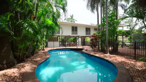 tropical tiled rounded pool area in rock garden with black gate