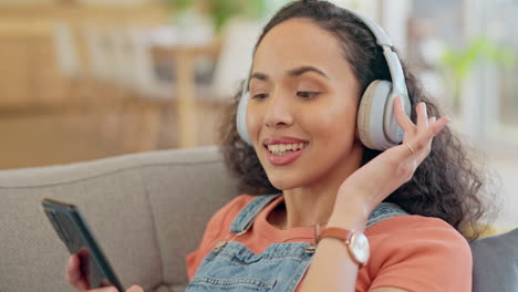 mujer, teléfono y auriculares en el sofá escuchando