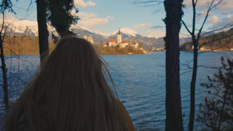 4k video of a beautiful young caucasian female sitting on a bench and looking over to island with the church on it