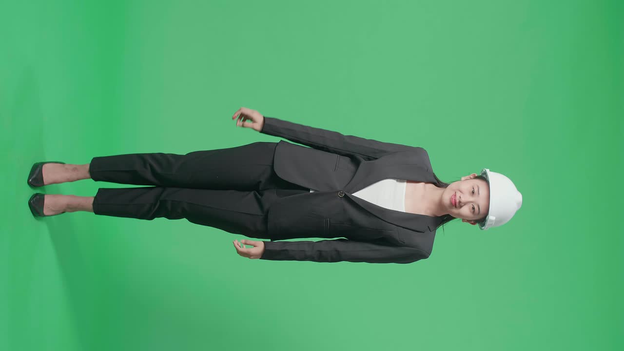Full Body Of Smiling Asian Female Engineer Putting On The Safety Helmet In The Green Screen Studio