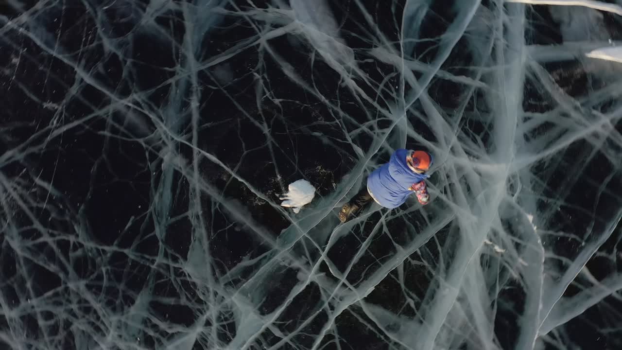 한 소녀가 겨울에 얼음 위에 누워서 팔과 다리를 으로 흔들며 천사를 묘사합니다.