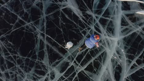 una niña yace en el hielo en invierno, agitando los brazos y las piernas hacia un lado, representando a un ángel.