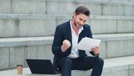 hombre de negocios leyendo periódicos de negocios al aire libre. gerente masculino celebrando la victoria