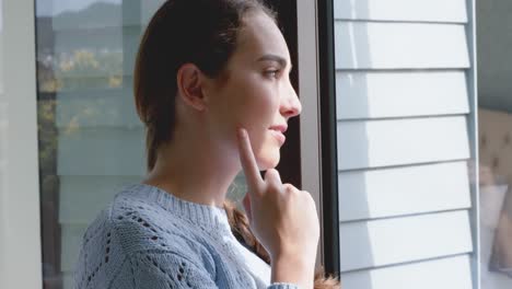 thoughtful caucasian woman smiling and looking through window in slow motion