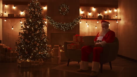 Santa-Claus-is-working-on-a-laptop-sitting-at-home-on-the-sofa-in-the-background-of-Christmas.-Santa-responds-to-children-emails.-High-quality-4k-footage