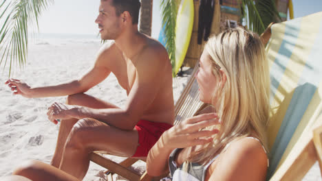 caucasian couple sitting on sunbeds on the beach