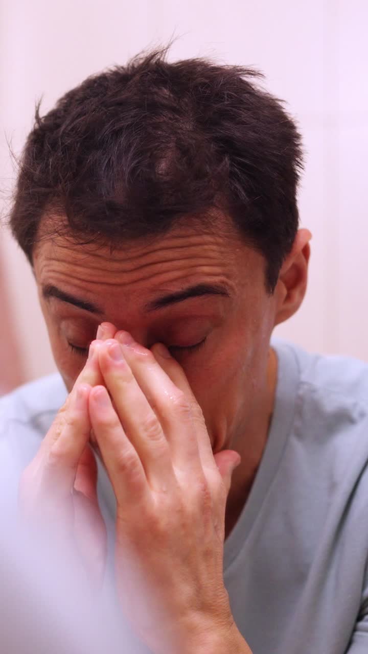 Sleepy man washing face in bathroom sink
