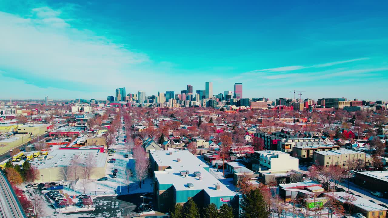 Denver’s downtown high-rises, snowy neighborhoods, and bright winter skies, showcasing modern urban growth.