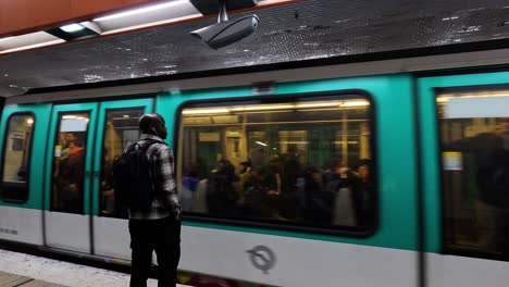 man waits as paris metro arrives at station