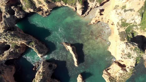 Vista-De-Pájaro-Giratoria-De-Acantilados-Y-Formaciones-Rocosas-De-La-Costa-Del-Mar-Atlántico,-Lagos,-Algarve