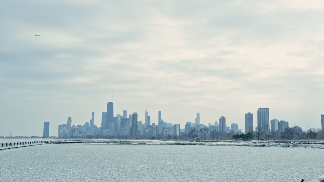 View of a city skyline over a lake on a gray day with clouds in the sky and buildings in the distance during winter time