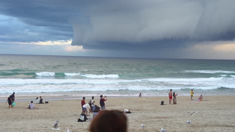 toma estática de la playa costera en el paraíso de los surfistas, una gruesa capa de ominosas nubes oscuras de tormenta que se extienden por el cielo, gente viendo un clima apocalíptico en la costa dorada, queensland, australia