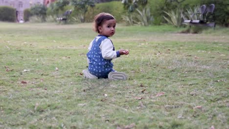 Un-Niño-Lindo-Tratando-De-Pararse-En-El-Césped-Verde-Del-Parque-Desde-Un-ángulo-Diferente