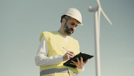 un ingeniero profesional con casco blanco comprueba el funcionamiento de las turbinas eólicas en un día soleado, lo que simboliza nuestro compromiso con la energía sostenible