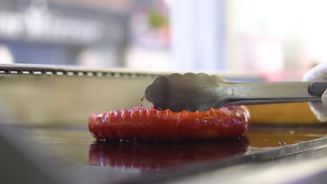 jefe de cocina en una tienda de comida rápida de ventana abierta colocando salchichas a la parrilla en cámara lenta