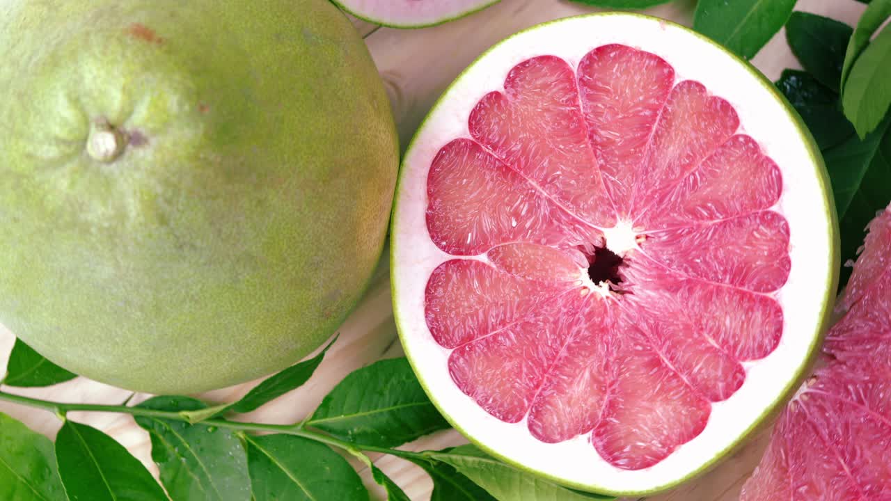 정원에서 나무 테이블에 잎을 가진 빨간 포멜로 과일을 회전, 나무 배경 4k 해상도에서 잎과 함께 빨간 포মেল로 과일.