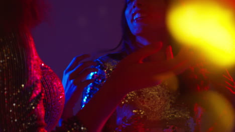 close up of two women in nightclub bar or disco dancing with sparkling lights 1