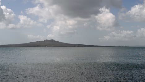 volcán inactivo rangitoto entre un hermoso paisaje nublado y el océano pacífico turquesa con la marea saliendo