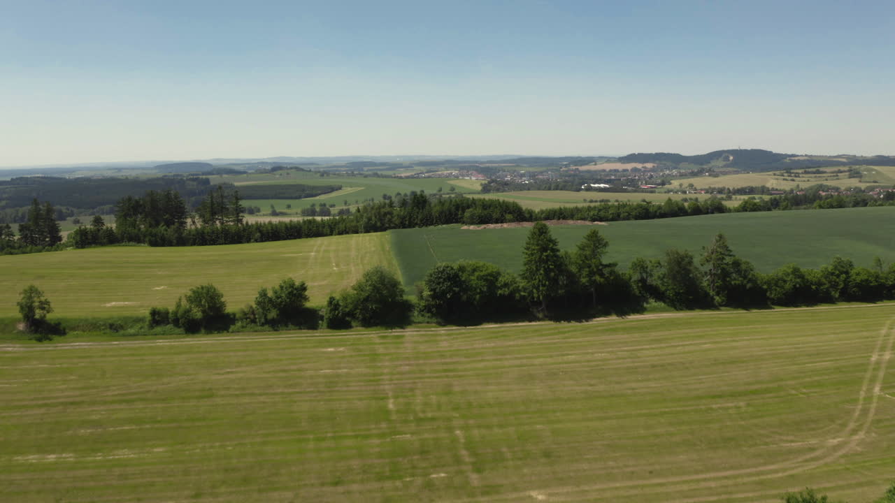 Rising up revealing gentle sloped agricultural fields and mountain foothills in the Czech Republic, aerial
