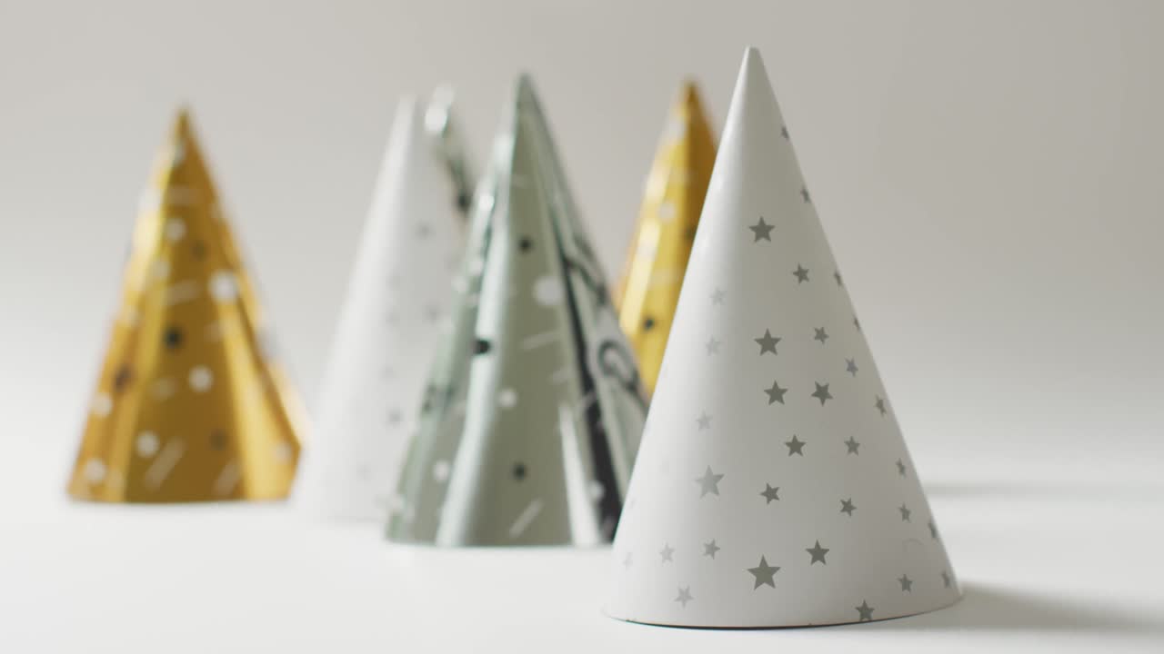 video de sombreros de fiesta blancos, dorados y plateados sobre un fondo gris pálido