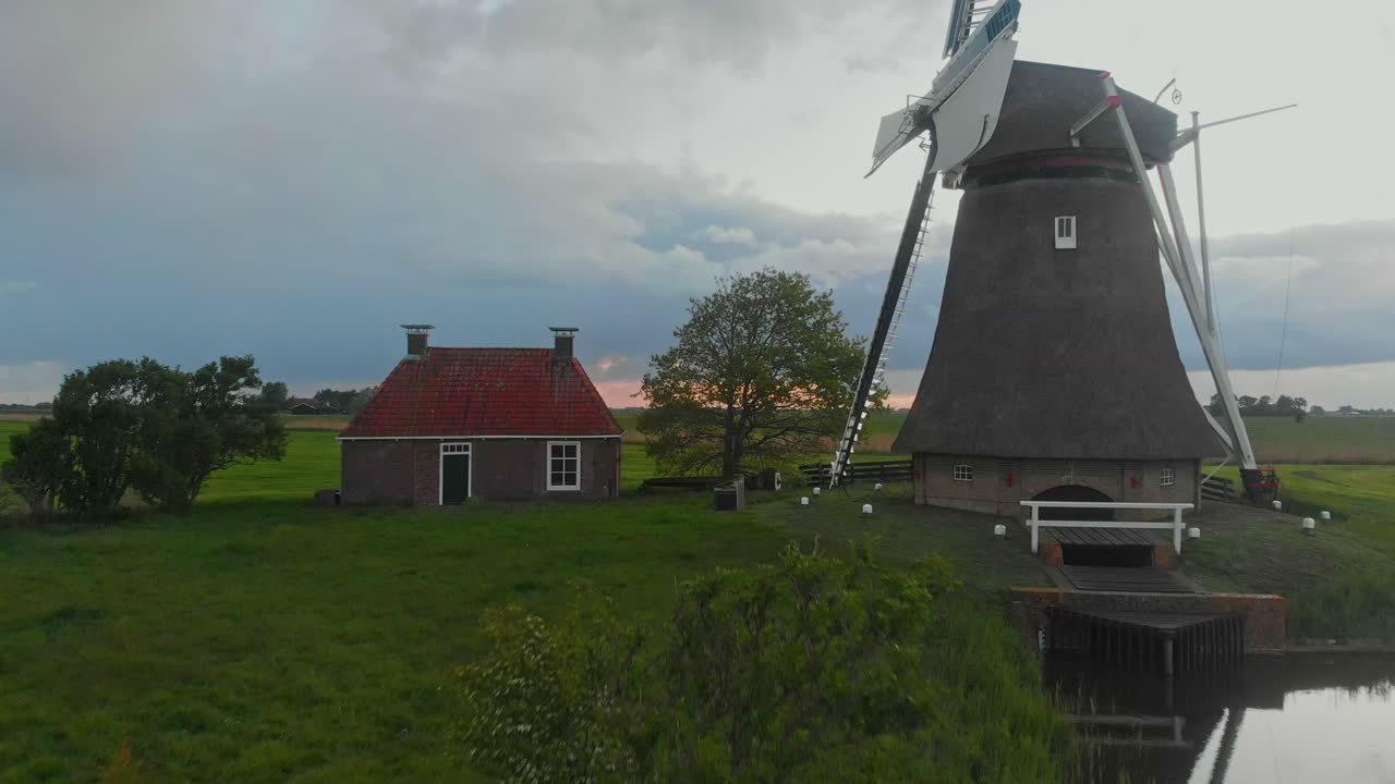 Veduta aerea di un mulino a vento e di una casa tradizionale durante l'alba a Lollum, Frisia, Paesi Bassi