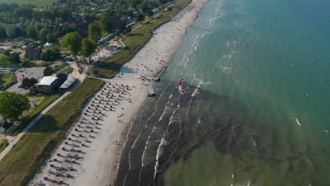 Vista-Aérea-De-Drones-De-Dos-Veleros-En-Una-Playa-Turística-En-La-Costa-Del-Mar-Báltico,-Scharbeutz,-Alemania,-Círculo-Pan,-Día