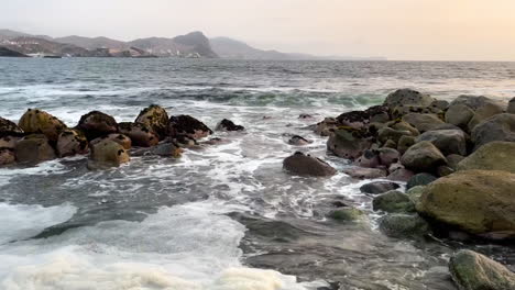 inclinar hacia arriba revela una toma de la orilla del mar con vistas a la cordillera al fondo en san bartolo, lima, perú