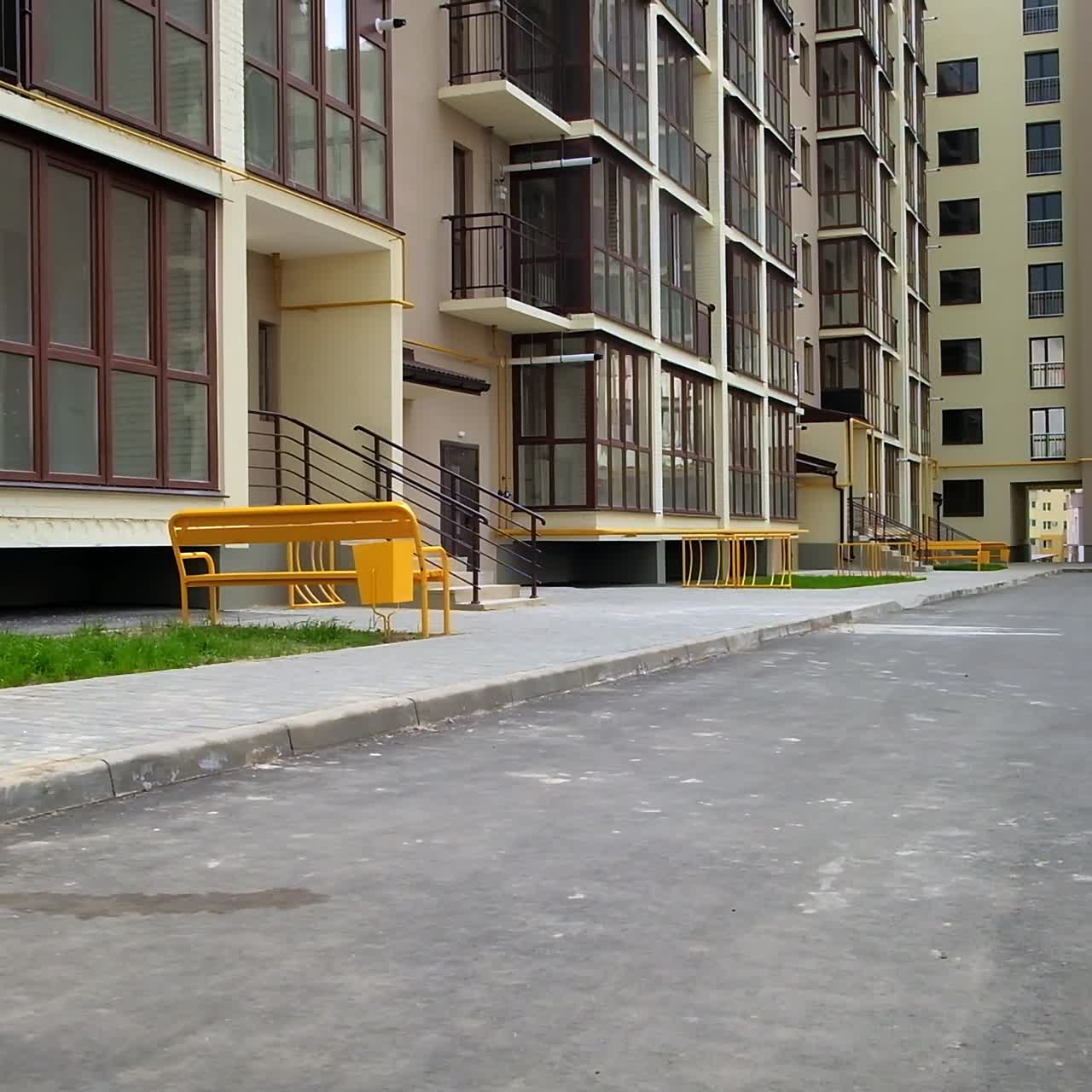 Beautiful facade of the newly constructed apartment building in the city. Yard with cars inside the angle-built house