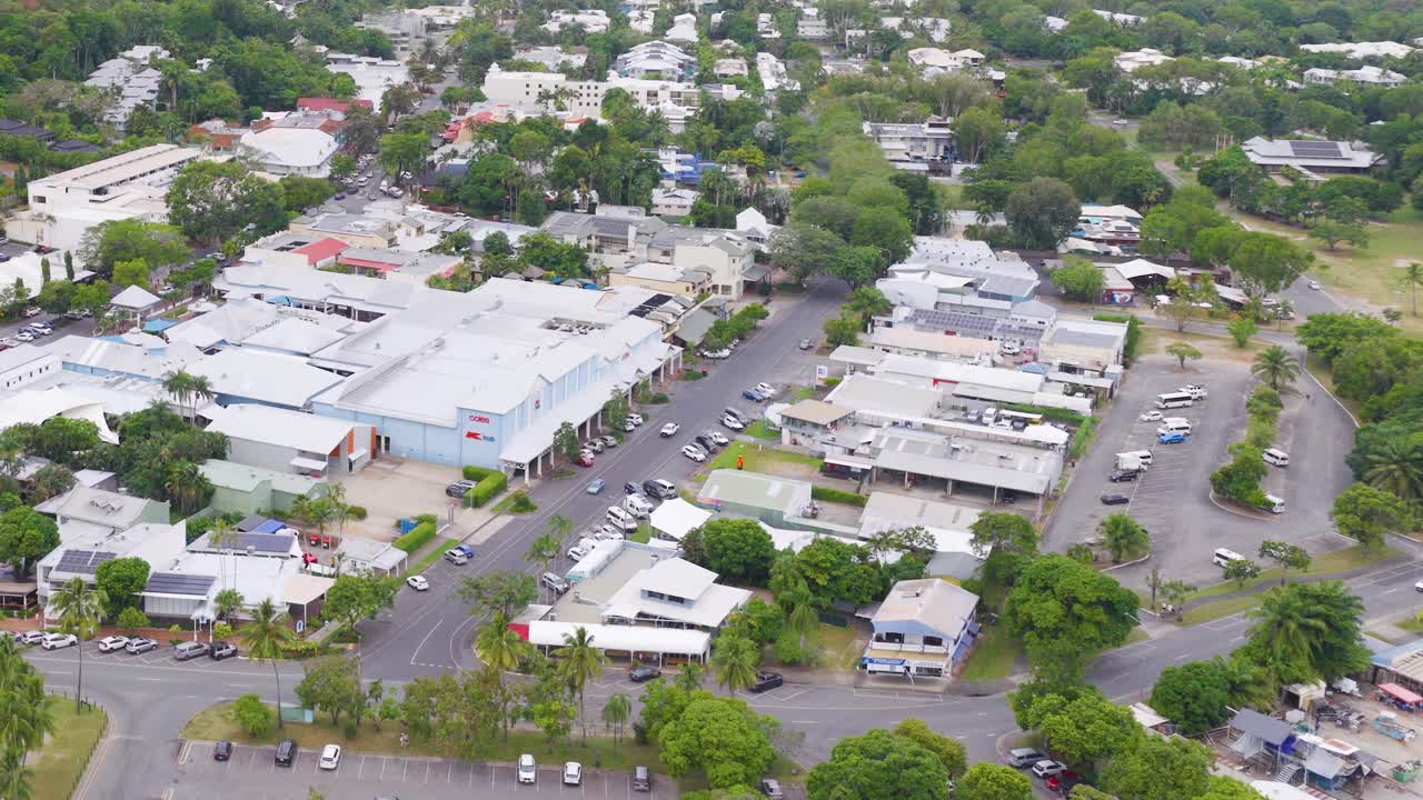 Aerial footage captures the streets and buildings of Port Douglas, Queensland, under bright daylight, showcasing urban layout and greenery
