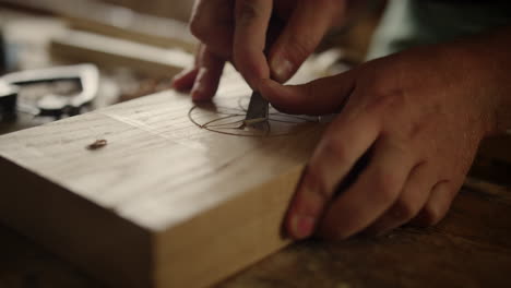 unrecognized man making wood carving indoors. male hands using tool in carpentry