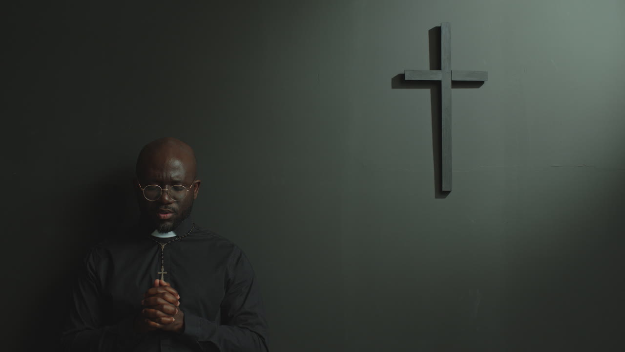 Black Priest Praying to God with Eyes Closed in Modern Minimalist Church