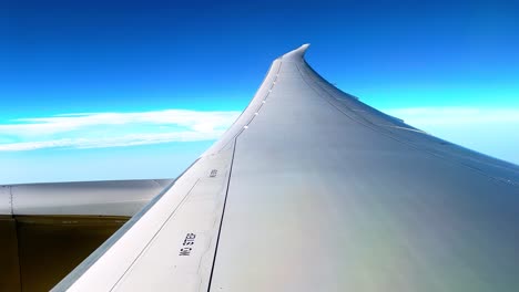 minimalist aerial view of a modern airplane wing soaring above clouds and blue sky, ideal for travel, aviation, and adventure-themed projects