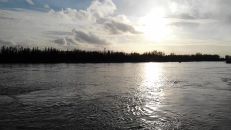 sunlight reflects through quiet lake during sunset in oude maas river near zwijndrecht, netherlands