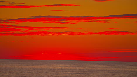time lapse of red colored clouds flying over ocean after spectacular sunset at horizon