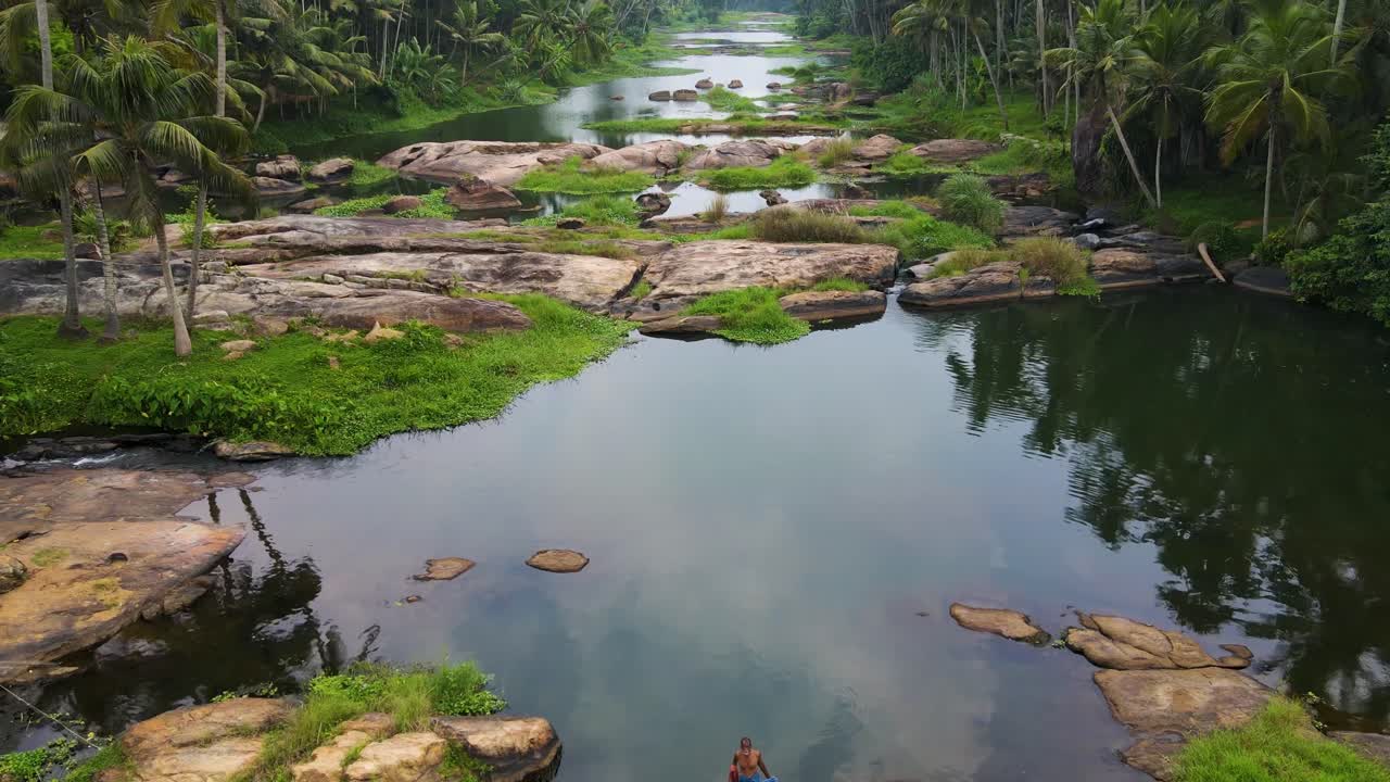 un drone aéreo filmado sobre el denso bosque de cocoteros de kerala, donde un río tranquilo serpentea a través de la exuberante vegetación.
