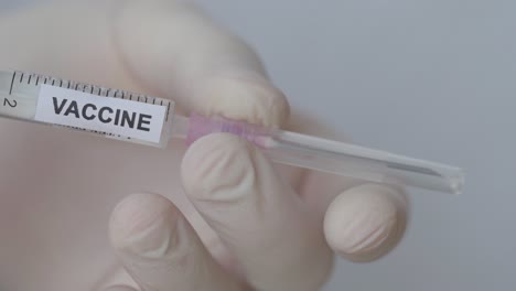 hand with glove removes the needle with cap of syringe - covid-19 vaccine