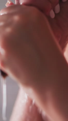 woman squeezes long hair after washing in shower unit closeup. lady does hair washing procedure in warm water sprays at home. bare woman enjoys bathing