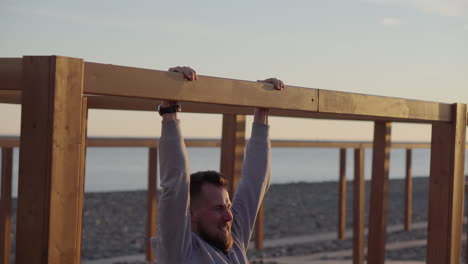 man doing pull-ups on the beach at sunset