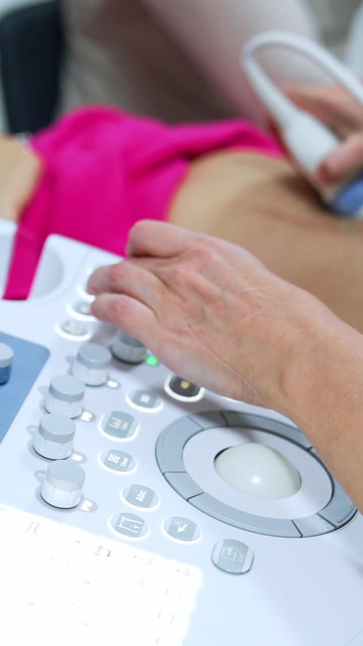 Ultrasound machine is used to check up the pregnancy development. Doctor moves the device by the belly of blonde woman. Vertical video