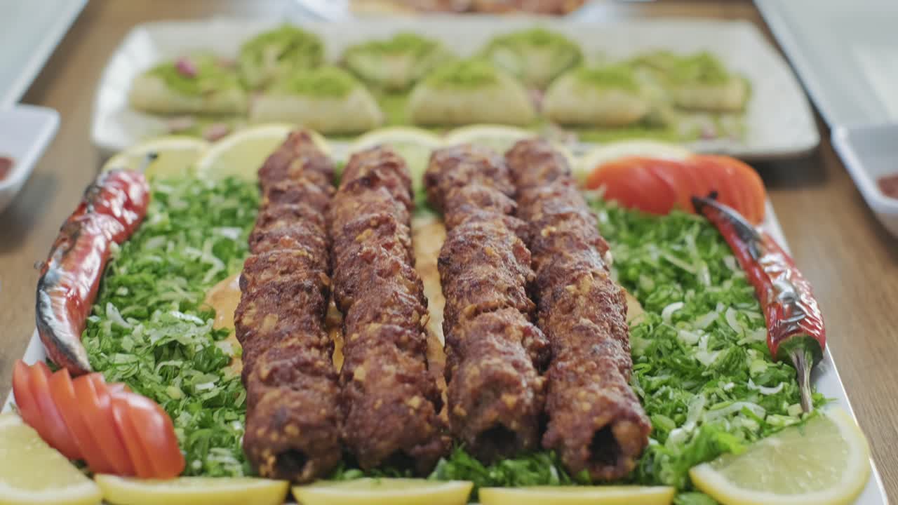 Camarero sirviendo un plato de kebab turco tradicional con cebolletas y tomates