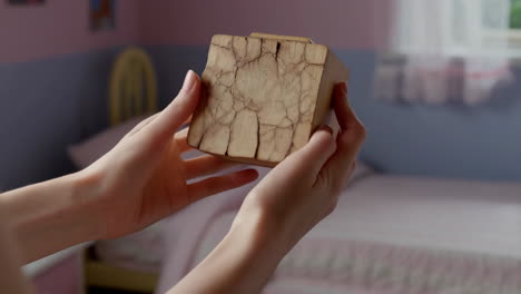 close-up of hands holding a weathered wooden block