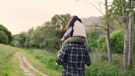 father carrying daughter on shoulders