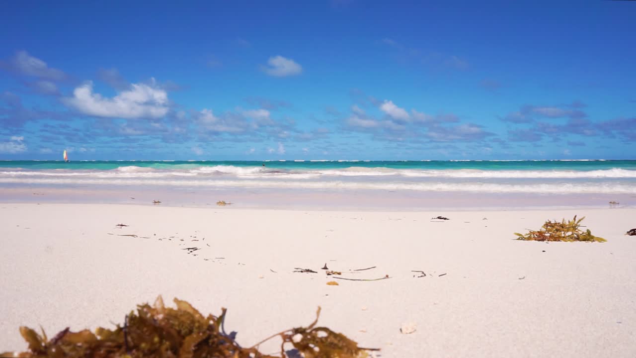 Gently Waves Caribbean white sand beach calm summer day scene cloudy blue sky boat passing by HD ground level shot