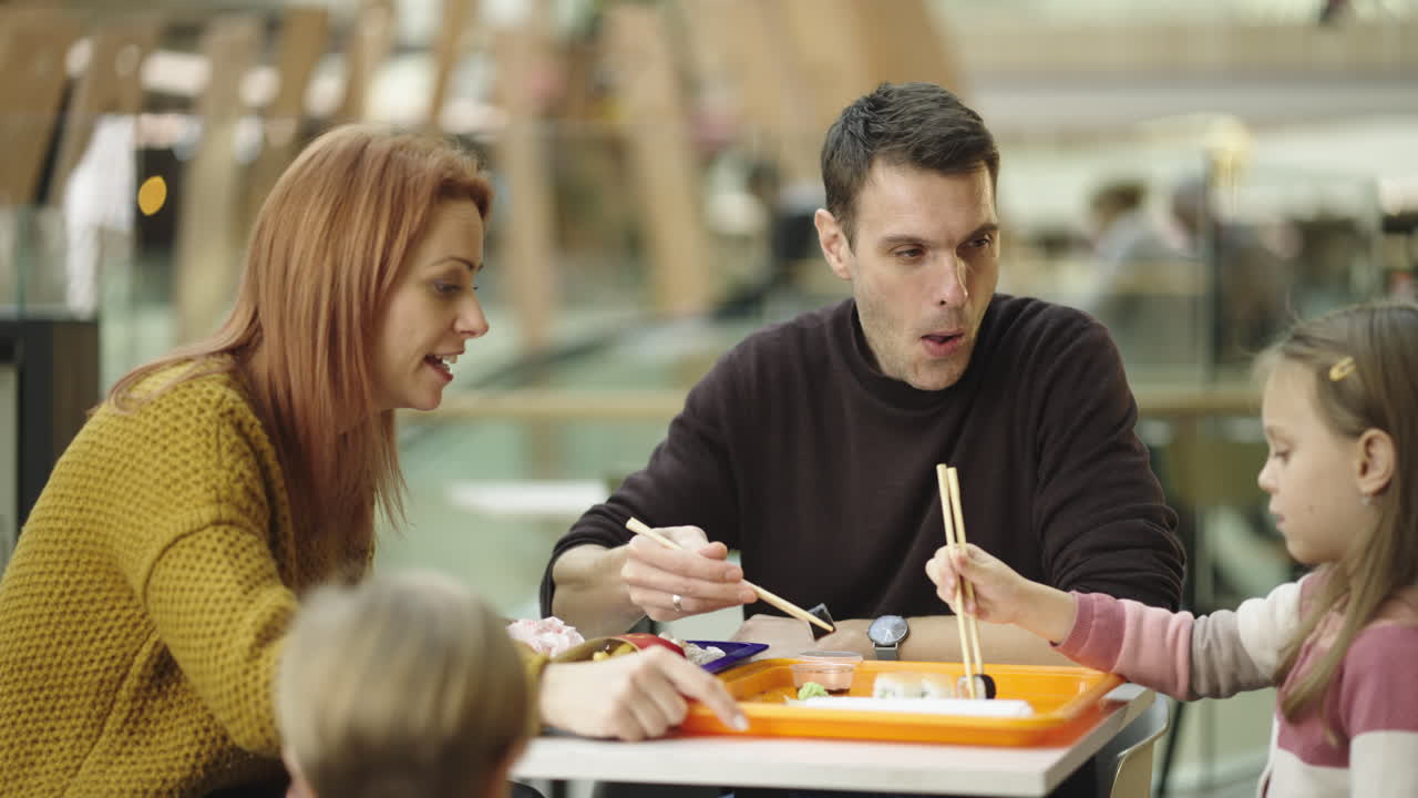 Family eating sushi together at a food court