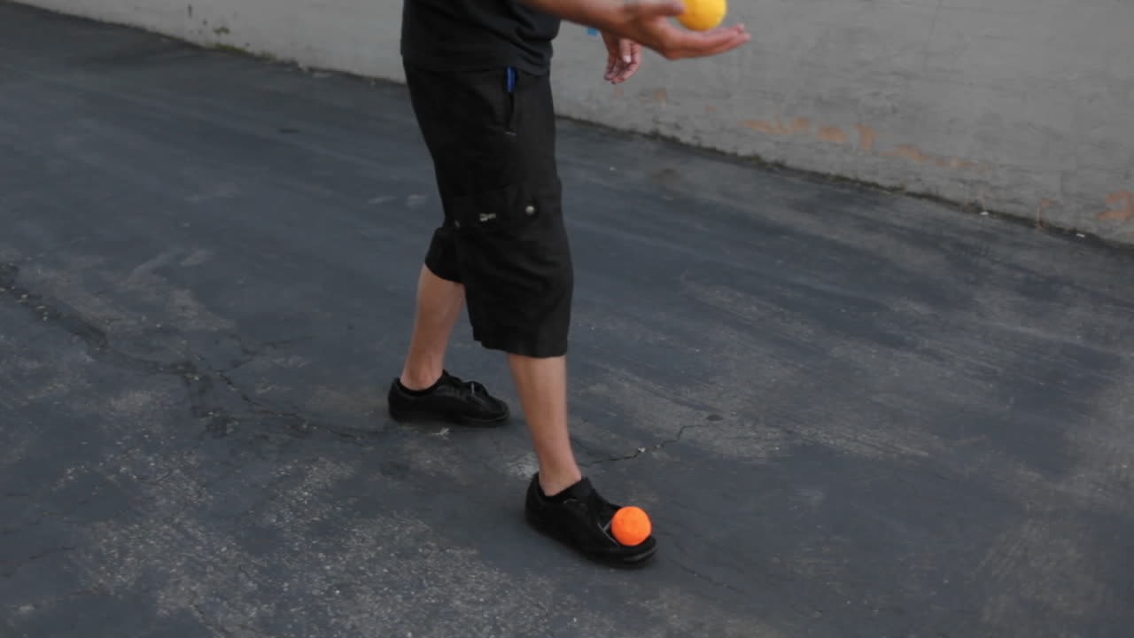 한 남자가 발로 공을 저글링한다